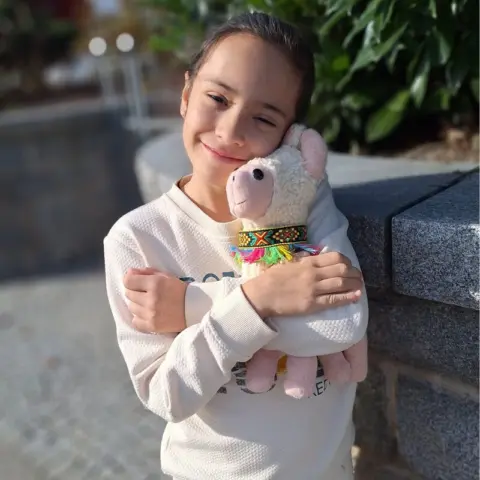 8jährige kuschelt mit selbst genähtem Alpaka 480x480 Mädchen hält glücklich lächelnd ein selbst genähtes Kuscheltier im Arm