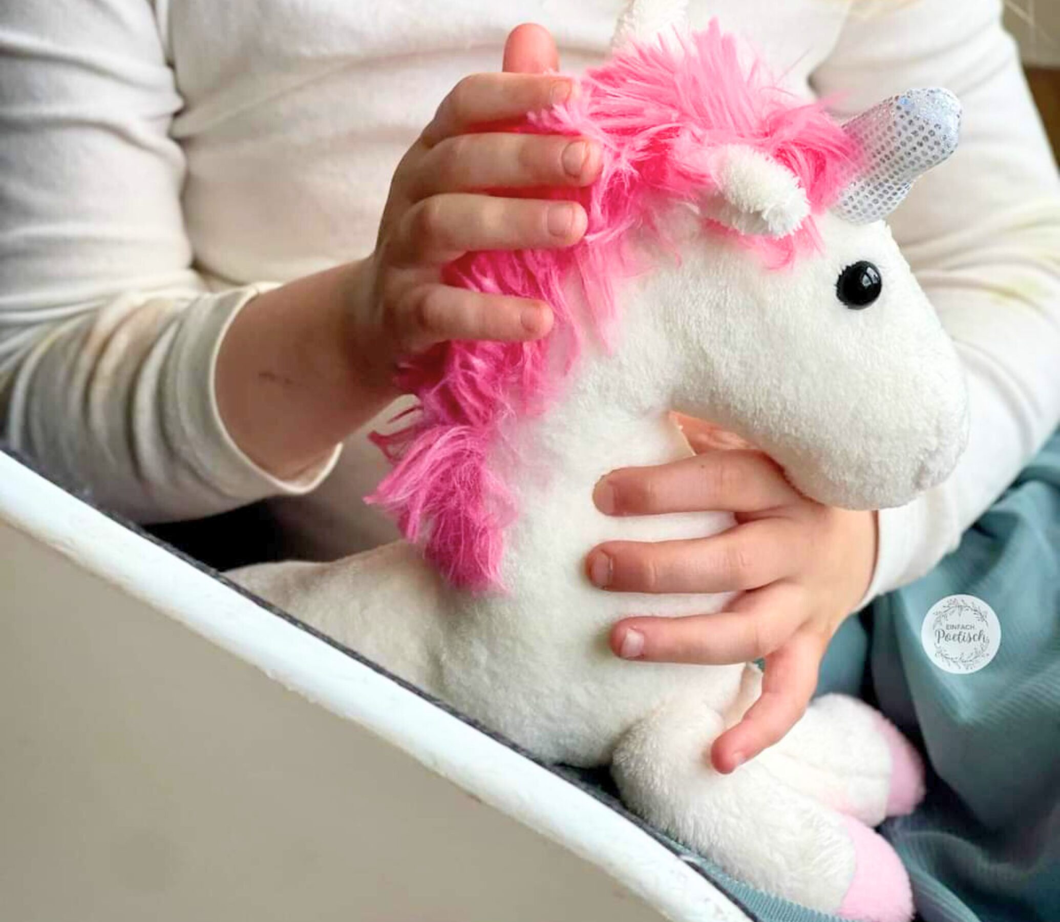 Ein Kind hält sein selbst genähtes Einhorn in den Händen und streichelt es
