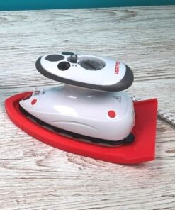 Das VERITAS Mini Steam Dampfbügeleisen mit Silikonmatte in einer Komplettansicht auf einer Holzunterlage stehend