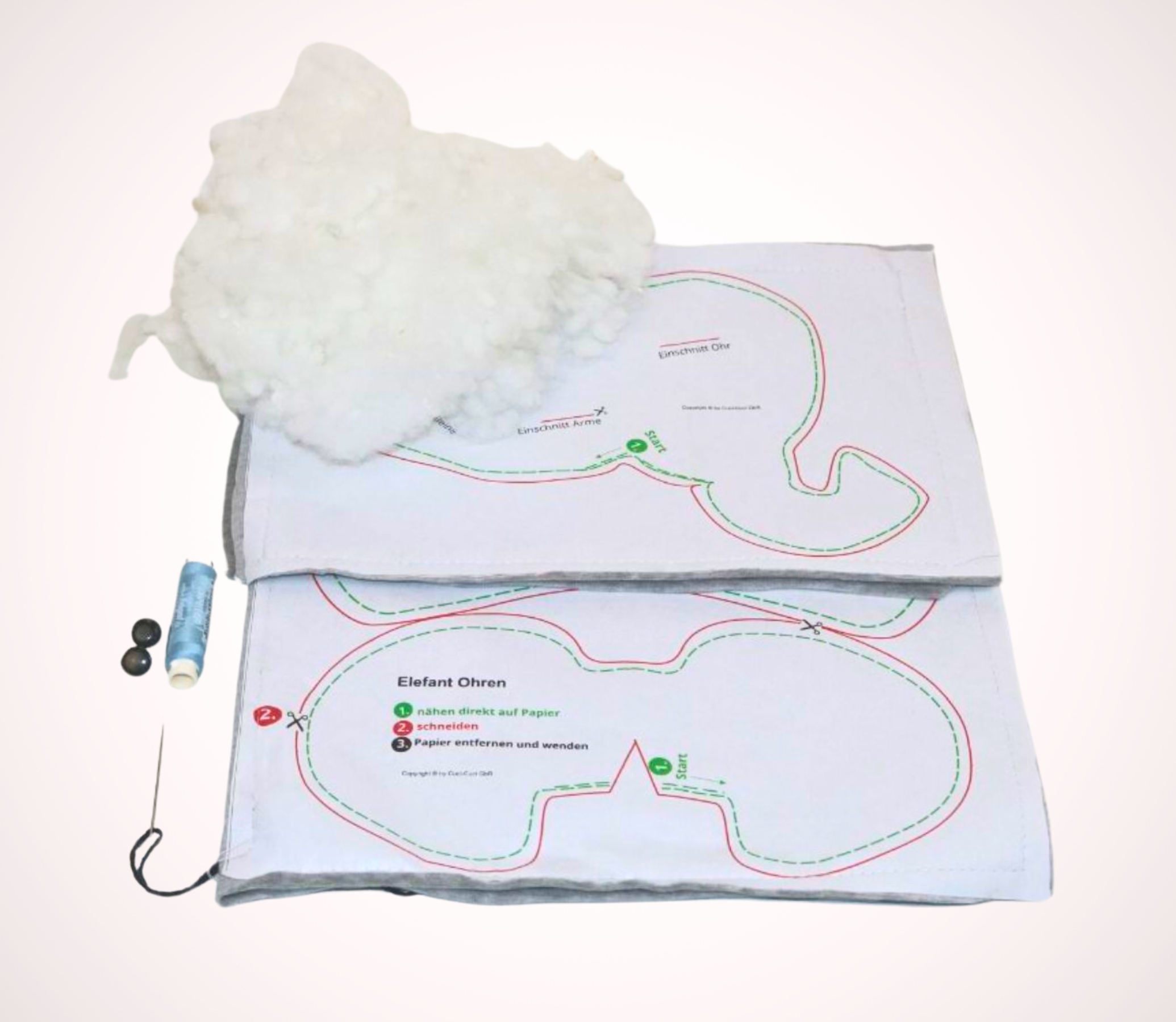 Paketinhalt von cuci cuci DIY Elefant zum Selbernähen mit Nähanleitung, Füllwatte, Nadel, Faden, Augen sowie dem Schnittmuster, das mit dem samtweichen Kuschelstoff aus Nicky-Baumwolle verbunden ist